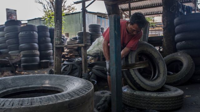Hombre en un taller trabajando con neumáticos usados