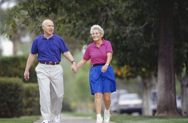 Una pareja mayor caminando por un barrio suburbano