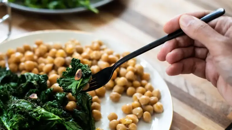 Qué vitaminas son fundamentales para la salud y qué alimento aporta la mayor variedad El difunto y gran comediante australiano Barry Humphries (famoso por su personaje Dame Edna) habló una vez con humor sobre los beneficios para la salud del kale (o col rizada). Solo un puñado, bromeó, contenía suficientes vitaminas, minerales y oligoelementos esenciales como para mantenerte sentado en el baño durante dos días enteros. Al parecer, no era lo suficientemente sabroso como para justificar una segunda ración. En un mundo en el que los "superalimentos" se comercializan sin descanso por su supuesta capacidad para aportarnos todos los nutrientes que necesitamos, vale la pena preguntarse: ¿qué vitaminas son realmente esenciales? Y, aparte de la col rizada (que, por cierto, me gusta bastante), ¿qué alimentos nos ayudan a cubrir nuestras necesidades diarias? Vitamina A Final de Más leídas La vitamina A, también conocida como retinol, se encuentra en alimentos como los huevos, el pescado azul y los productos lácteos. Desempeña un papel fundamental en el mantenimiento de la salud de la piel y el sistema inmunológico. Pie de foto,La vitamina A, también conocida como retinol, se encuentra en alimentos como los huevos. Pero probablemente sea más conocida por su contribución a la visión. La vitamina A se une a los pigmentos sensibles a la luz de las células de los conos y bastones de la retina, lo que ayuda a ver, especialmente en condiciones de poca luz. La deficiencia de vitamina A, aunque poco común en los países ricos, puede provocar graves problemas de visión e incluso ceguera. Otra fuente de vitamina A es el betacaroteno, que se encuentra en frutas y verduras de colores vivos como las zanahorias, los pimientos, las espinacas y la calabaza. El cuerpo convierte el betacaroteno en vitamina A, por lo que asociamos las zanahorias con la visión en la oscuridad. Vitamina B Las vitaminas B son una familia de ocho nutrientes diferentes, cada uno con su propio número y función. La vitamina B1 (tiamina) ayuda al sistema nervioso y favorece la digestión. Las personas con alcoholismo crónico corren un riesgo especial de sufrir deficiencia, lo que puede provocar el síndrome de Wernicke-Korsakoff, un trastorno neurológico grave que afecta a la memoria y al movimiento. Fuente de la imagen,Getty Images Pie de foto,Las vitaminas B se encuentran en todo tipo de alimentos, desde legumbres y leguminosas hasta carne, pescado y lácteos. La B2 (riboflavina) y la B3 (niacina) tienen funciones similares, mientras que la B9 (folato) y la B12 (cobalamina) son esenciales para la producción de glóbulos rojos. La falta de cualquiera de ellas puede provocar anemia. El folato es especialmente importante al inicio del embarazo, ya que ayuda a prevenir defectos del tubo neural como la espina bífida. Por eso se recomienda a las personas embarazadas o que están intentando concebir. Las vitaminas B se encuentran en todo tipo de alimentos, desde legumbres y leguminosas hasta carne, pescado y lácteos; una amplia familia de nutrientes en una gran variedad de alimentos. Vitamina C La vitamina C (ácido ascórbico) es la vitamina a la que recurrimos cuando nos sentimos mal, ya sea por un virus o por una resaca, y se la conoce como la vitamina "curativa" por una buena razón. Favorece la cicatrización de las heridas, ayuda a la reparación de los tejidos y contribuye al mantenimiento de los vasos sanguíneos y los huesos. La deficiencia de vitamina C provoca escorbuto, una enfermedad que antes era común entre los marineros, con síntomas como fatiga, hematomas, depresión y enfermedades de las encías. Fuente de la imagen,Getty Images Pie de foto,La vitamina C se encuentra principalmente en los cítricos. Afortunadamente, la vitamina C se encuentra en muchas frutas y verduras diferentes, especialmente en los cítricos. Por eso, a los marineros británicos del siglo XIX se les daba limas para prevenir el escorbuto, lo que les valió el apodo de "limeys". Vitamina D La vitamina D es esencial para los huesos, los dientes y los músculos. Se puede absorber a través de la dieta, especialmente del pescado azul, los huevos y la carne, pero el cuerpo también la produce en la piel gracias a la luz solar. En verano, la mayoría de las personas obtienen suficiente vitamina D al estar al aire libre. Sin embargo, en los meses de invierno, la dieta y, si es necesario, los suplementos cobran mayor importancia. La deficiencia es más común, especialmente en zonas con exposición solar limitada. Puede provocar huesos blandos y debilitados y síntomas como dolor óseo, fracturas y deformidades, incluida la clásica apariencia de piernas arqueadas. En los niños, esta afección se conoce como raquitismo; en los adultos, se denomina osteomalacia. Vitamina E A menudo pasada por alto, la vitamina E ayuda a proteger las células, favorece la visión y refuerza el sistema inmunológico. Se encuentra en los frutos secos, las semillas y los aceites vegetales, y suele ser fácil obtenerla en cantidades suficientes a través de una dieta variada. Fuente de la imagen,Getty Images Pie de foto,Los frutos secos son una gran fuente de vitamina E. Vitamina F (más o menos) En realidad no es una vitamina, la "vitamina F" es solo un apodo para dos ácidos grasos omega: el ácido alfa-linolénico (ALA) y el ácido linoleico (LA). Estas grasas esenciales favorecen el funcionamiento del cerebro, reducen la inflamación y ayudan a mantener la piel y las membranas celulares sanas. Como técnicamente no son vitaminas, las dejaremos pasar discretamente. Vitamina K No, no te has perdido las vitaminas G a J: simplemente se les ha cambiado el nombre con el paso de los años. Pero la vitamina K es real y es fundamental para la coagulación de la sangre. Fuente de la imagen,Getty Images Pie de foto,La vitamina K -que se obtiene a través de alimentos como las verduras de hoja verde y los cereales- es fundamental para la coagulación de la sangre. Las deficiencias son más comunes en los niños y pueden provocar hematomas y hemorragias difíciles de detener. Los suplementos son eficaces y se administran después del nacimiento. La mayoría de los adultos obtienen la cantidad suficiente a través de alimentos como las verduras de hoja verde y los cereales. Y el ganador es... Todas estas vitaminas son importantes, y todas se encuentran en una amplia variedad de alimentos cotidianos. Pero, ¿qué alimento proporciona la mayor variedad? El kale, el pescado azul y los huevos ocupan los puestos segundo, tercero y cuarto. Pero el número uno es: el hígado. Fuente de la imagen,Getty Images Pie de foto,El hígado es tan rico en vitamina A que se recomienda consumirlo solo una vez a la semana para evitar la toxicidad. Sí, el hígado. Ese alimento que tanto temíamos de niños y que solía servirse demasiado cocido en los comedores escolares. Pero también es rico en vitaminas A, B, D y K. De hecho, es tan rico en vitamina A que se recomienda consumirlo solo una vez a la semana para evitar la toxicidad por vitamina A, y no consumirlo en absoluto si se está embarazada. A veces, simplemente no se puede ganar.
